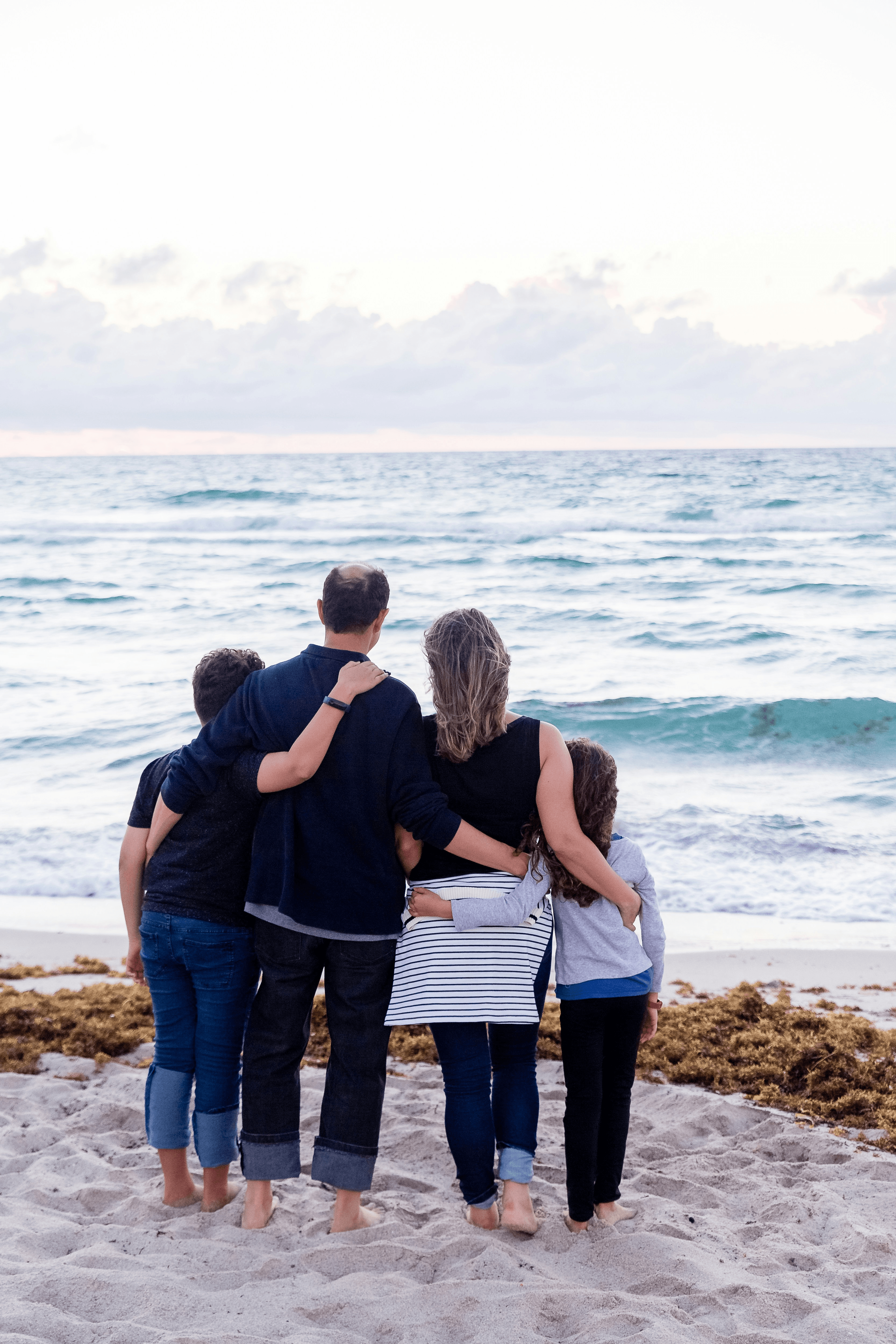Familia abrazada mirando al mar